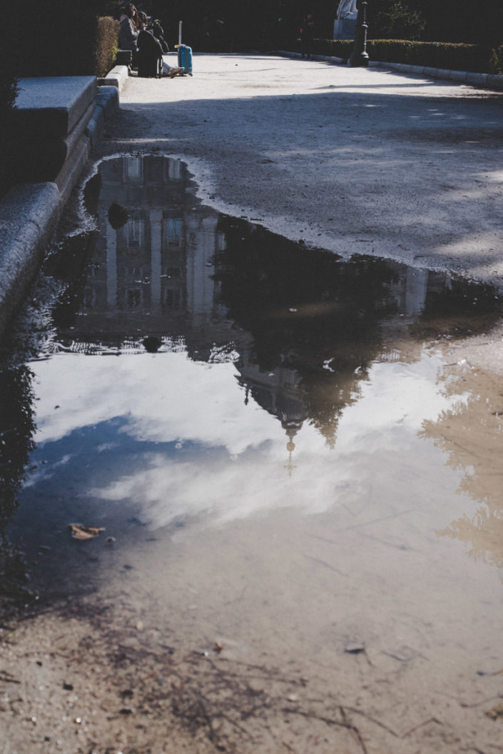 Street photography of the Royal Palace of Madrid as seen upside down from a puddle, street photography del Palazzo Reale di Madrid visto capovolto da una pozzanghera