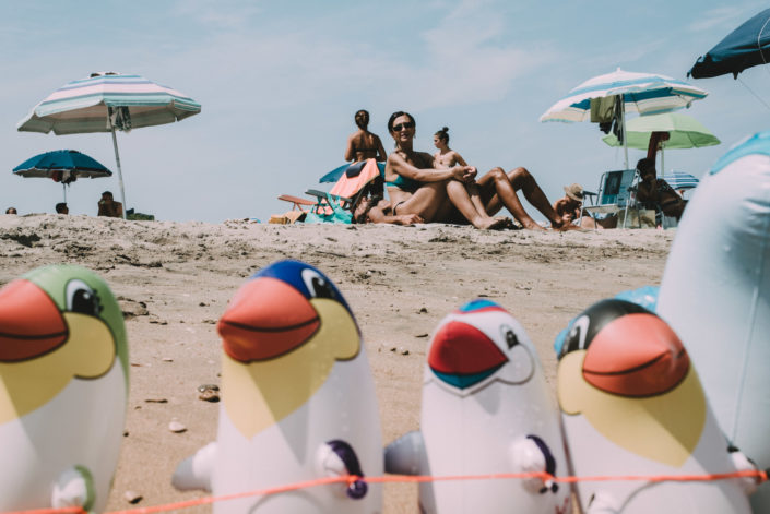 street photography of a lady on the beach framed by beach rubber toys, una signora in spiaggia con in primo piano giocattoli di gomma