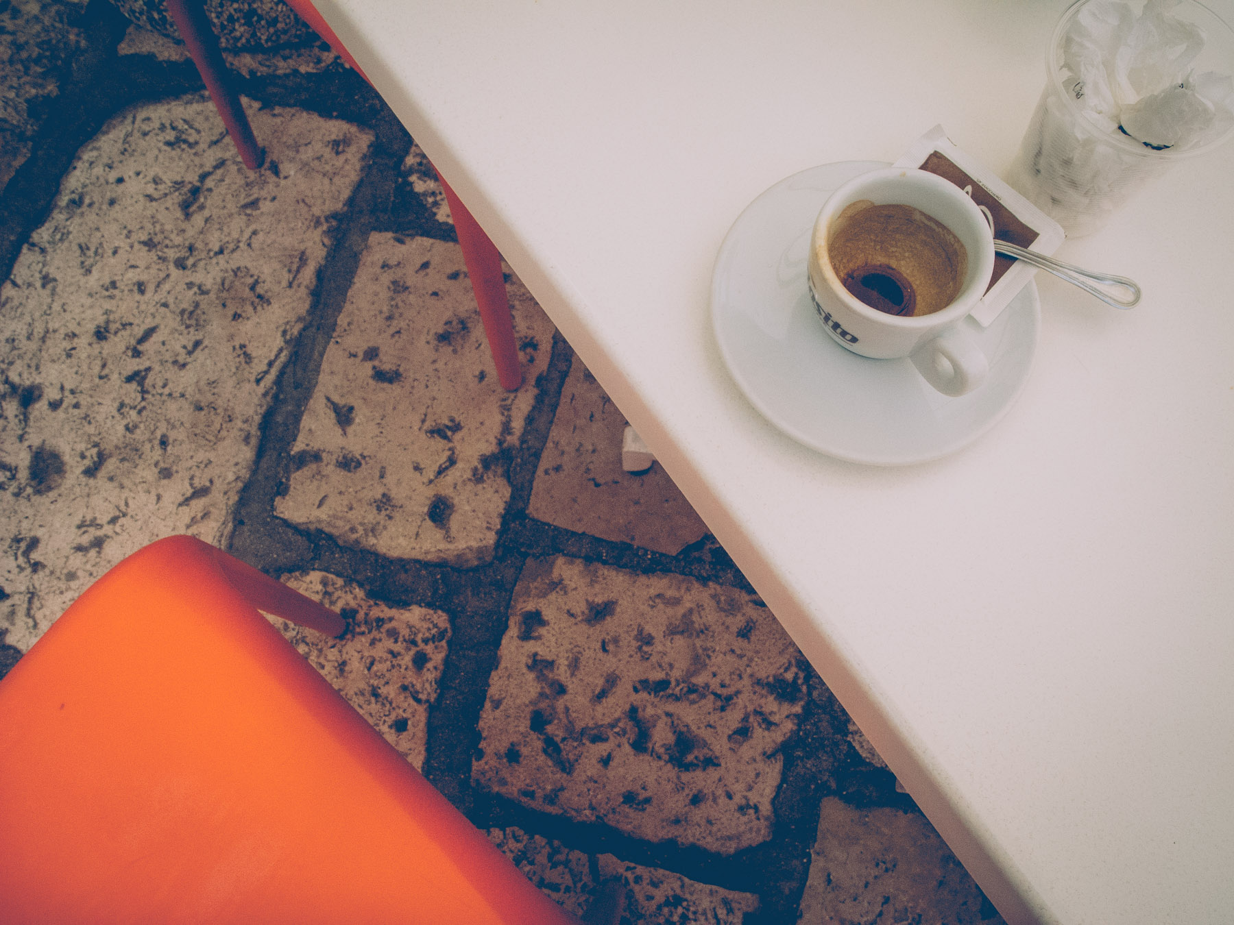 a coffee on a white table with an orange chair in Barletta