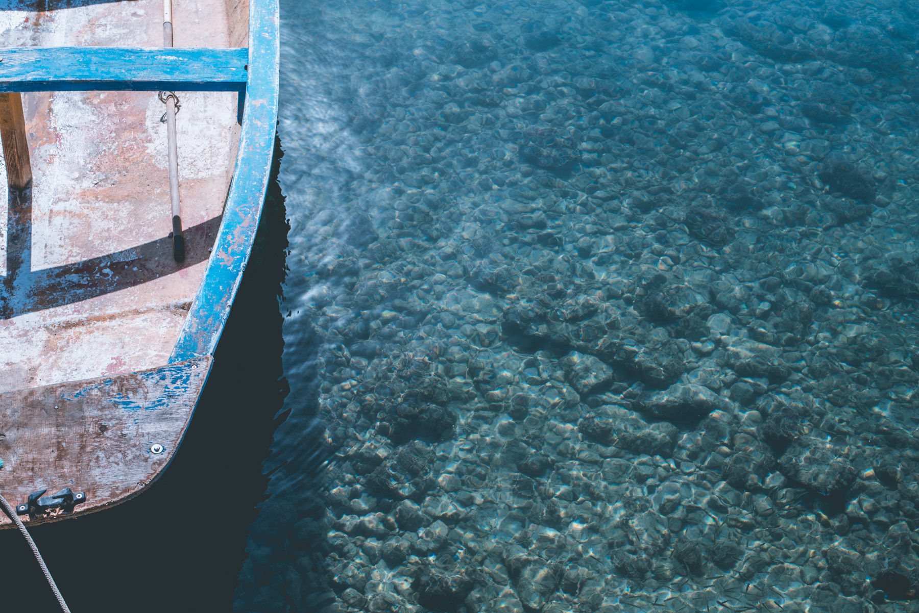 Detail of the blue sea of the island of lampedusa and a small section of a wooden boat