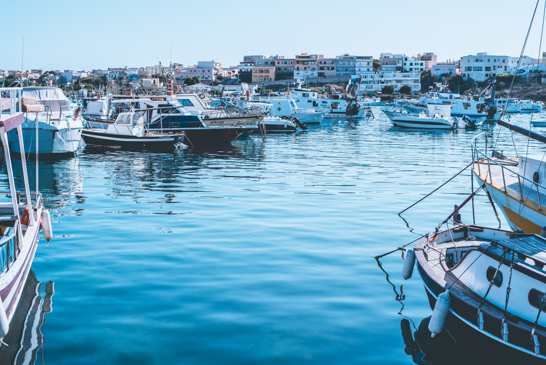 the harbour of Lampedusa with the blue sea and many boats
