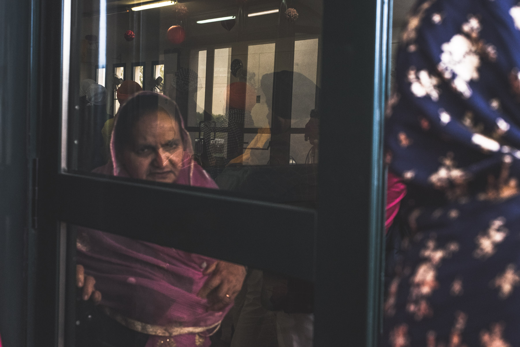 Al old Sikh lady solemny looking ahead of her through a window while attending Vaisakhi in Novellara