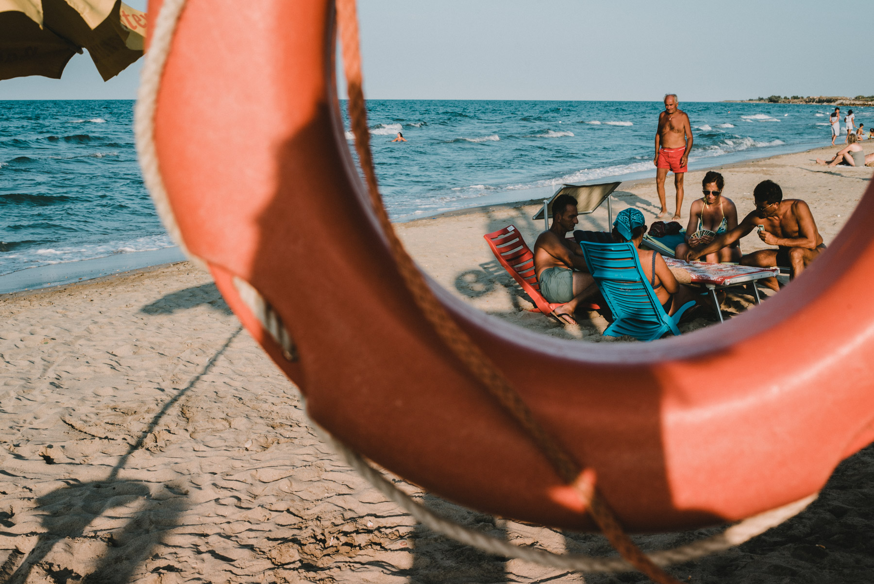 Some friends having fun and playing cards on the beach by the sea in the city of Barletta in Apulia, alcuni amici si divertono in spiaggia giocando a carte vicino al mare nella città di barletta in Puglia