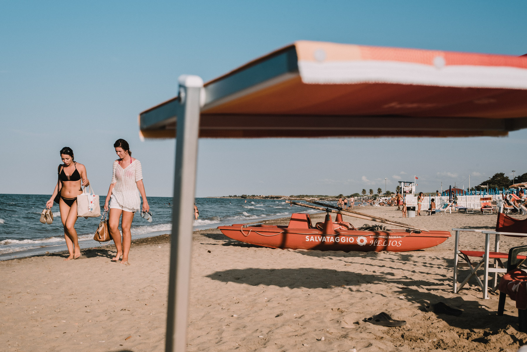two girls having a stroll on the beach by the sea in the city of Barletta in Apulia, due ragazze fanno una passeggiata in spiaggia al mare a Barletta in Puglia