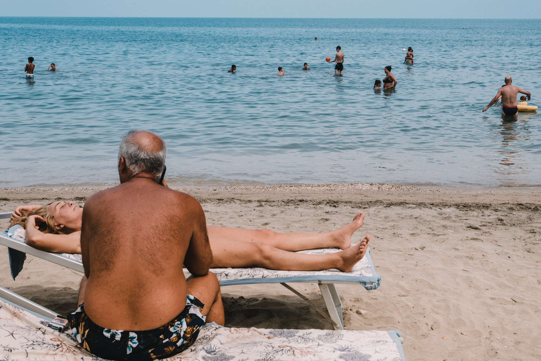 a couple having some relaxing time at the beach by the sea in the city of Barletta in Apulia, una coppia si rilassa in spiaggia durante una giornata al mare a Barletta in Puglia