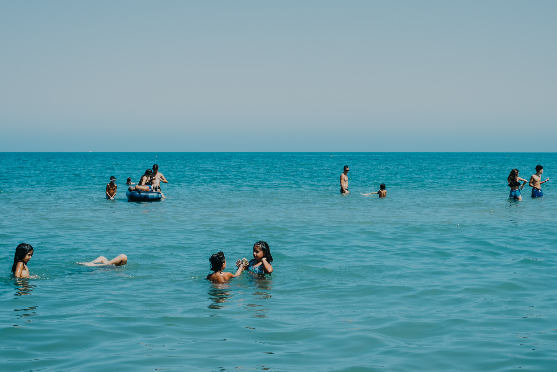 People anche children playing at the beach in the blue sea in the mediterranean sea in the city of Barletta, Apulia