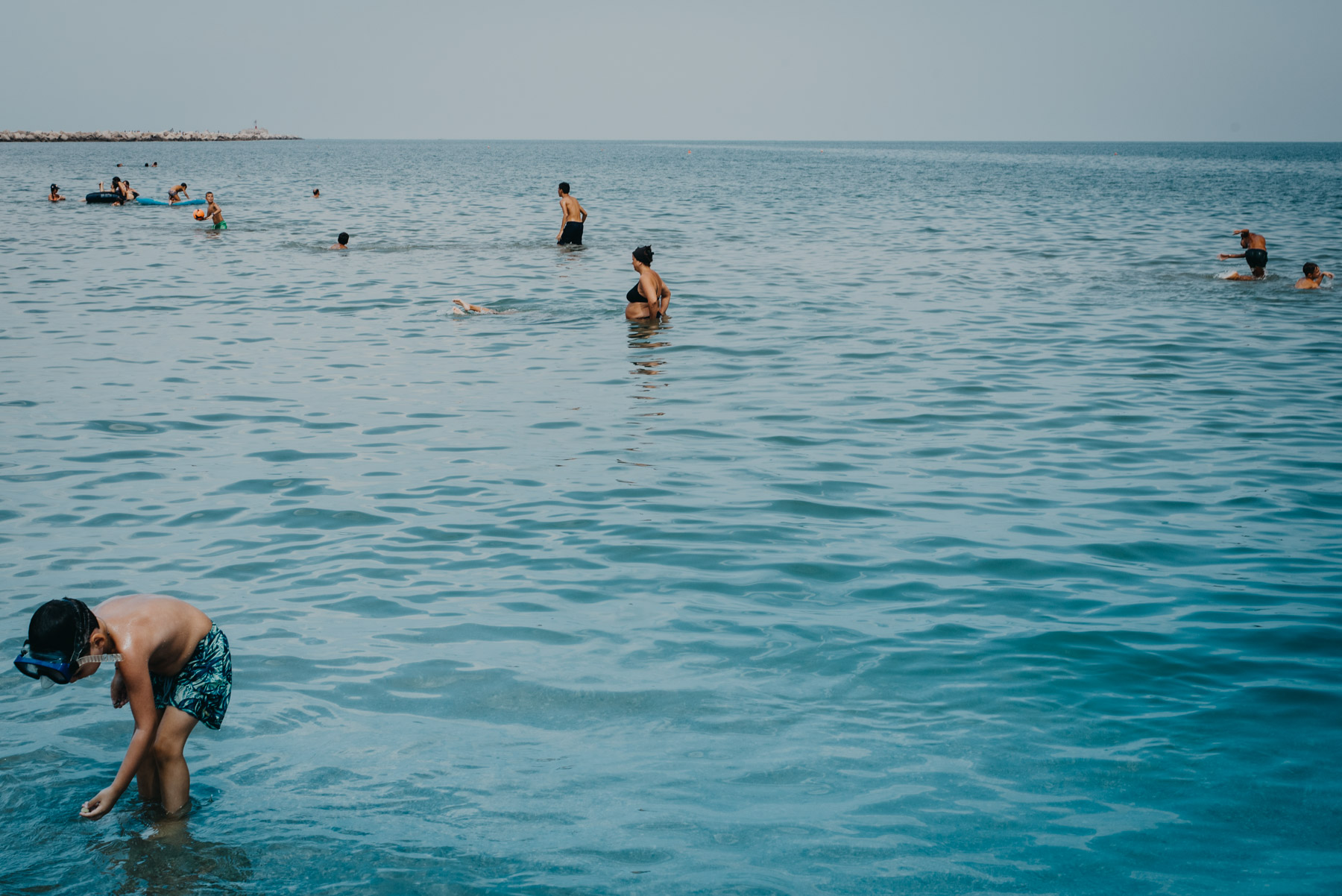People anche children playing at the beach in the blue sea in the mediterranean sea in the city of Barletta, Apulia