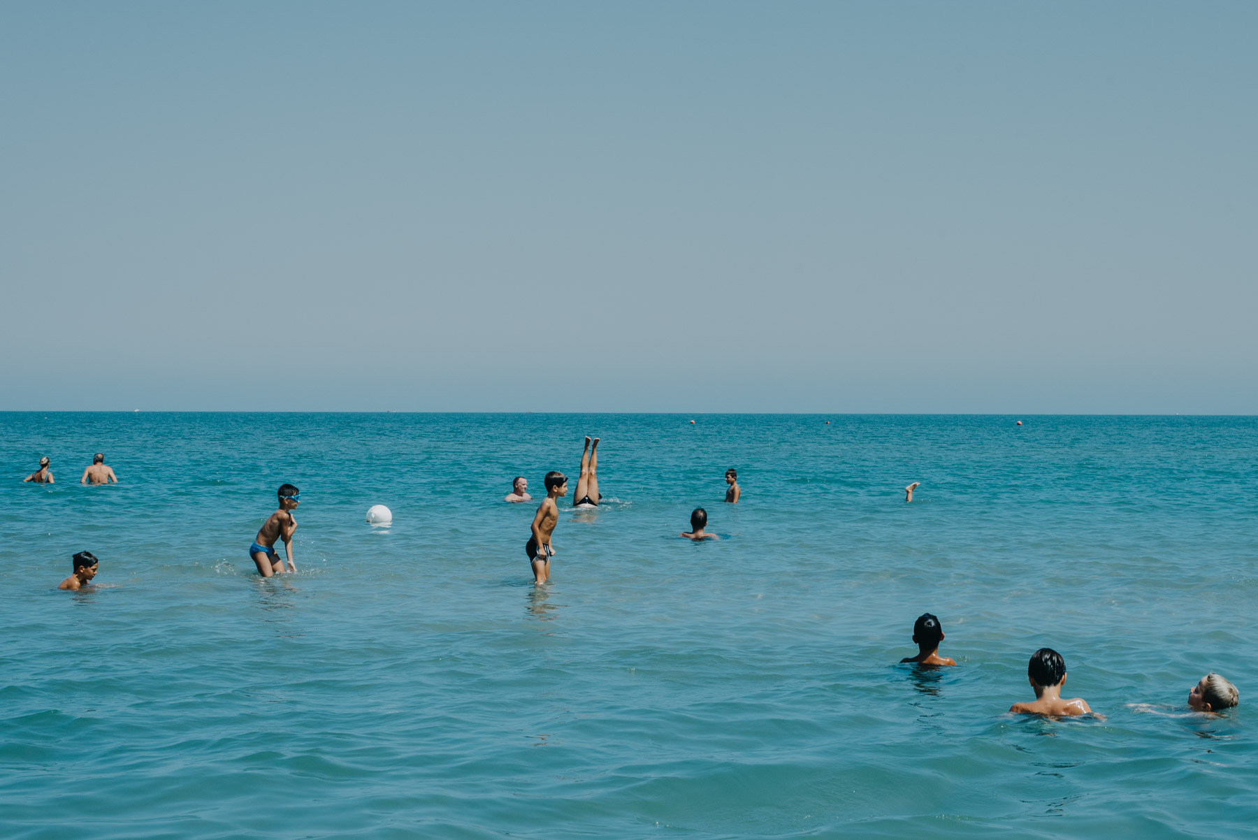 People anche children playing at the beach in the blue sea in the mediterranean sea in the city of Barletta, Apulia