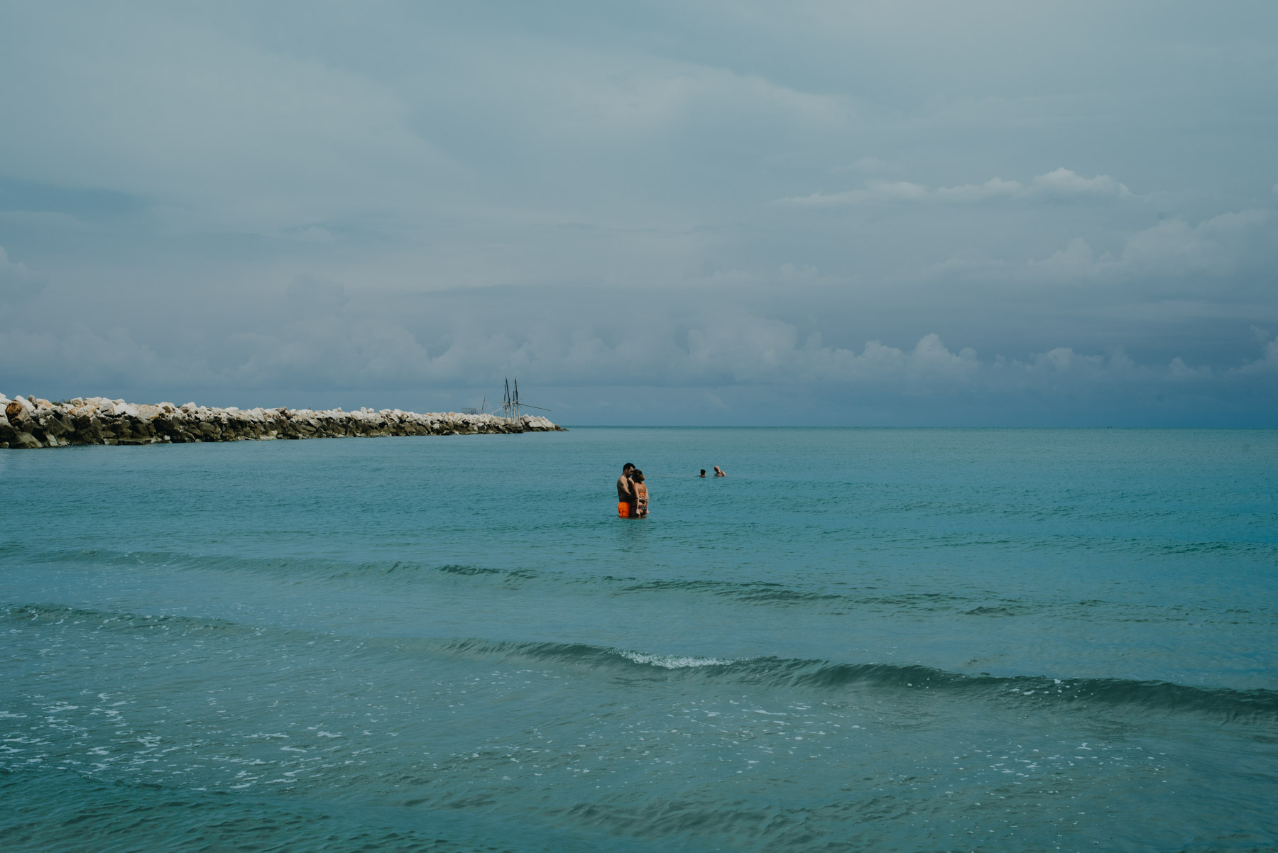 People anche children playing at the beach in the blue sea in the mediterranean sea in the city of Barletta, Apulia