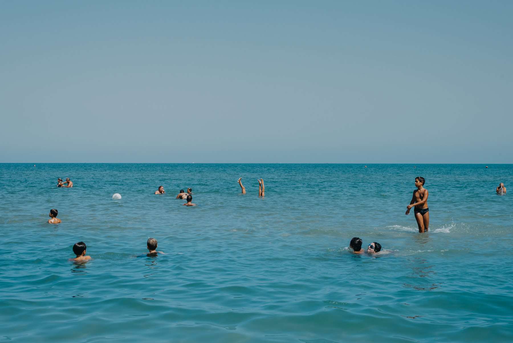People anche children playing at the beach in the blue sea in the mediterranean sea in the city of Barletta, Apulia