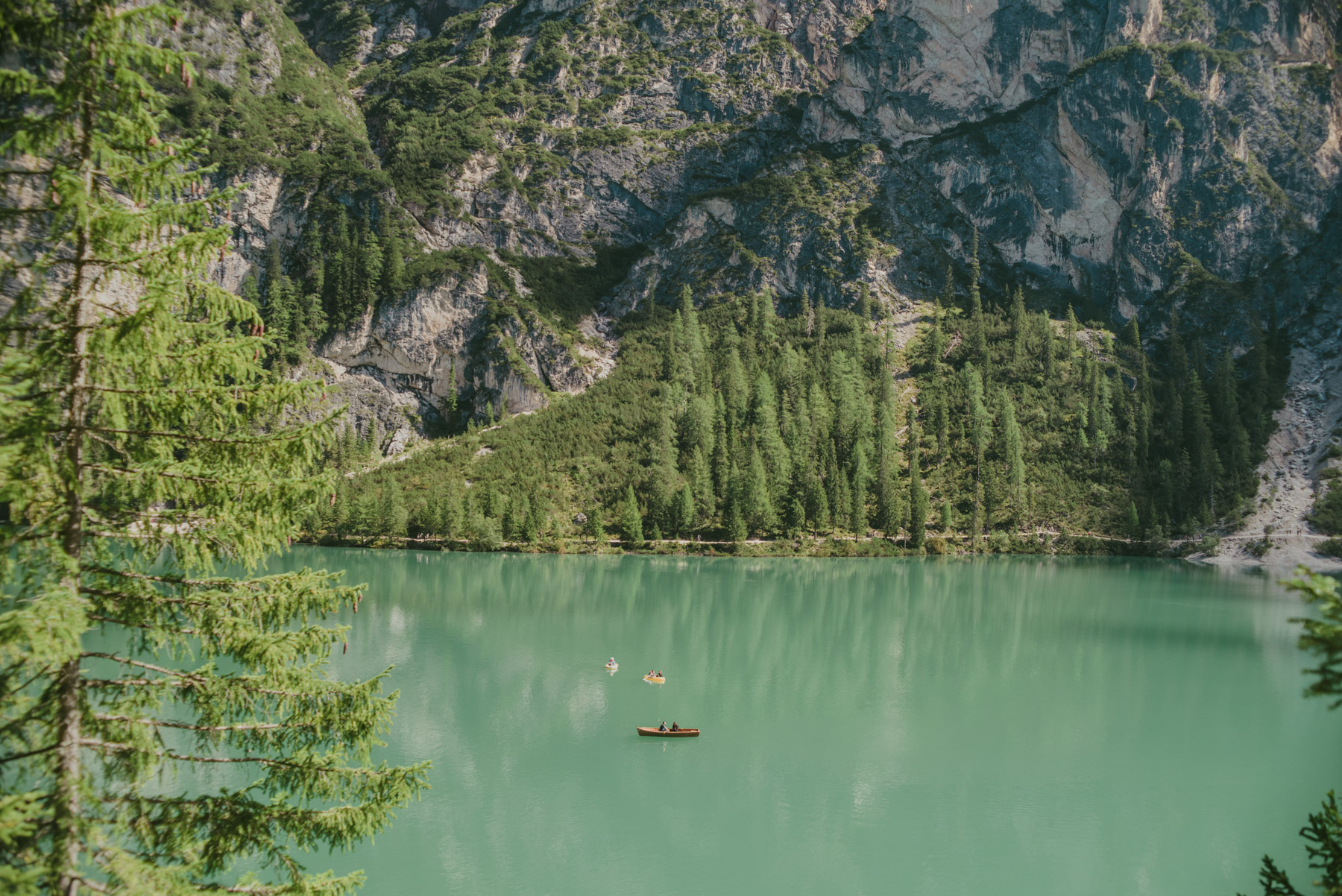 A panoramic view of Braies Lake on the Dolomites with some little boat floating on it ; una veduta panoramica del lago di Braies con piccole barche sullo sfondo