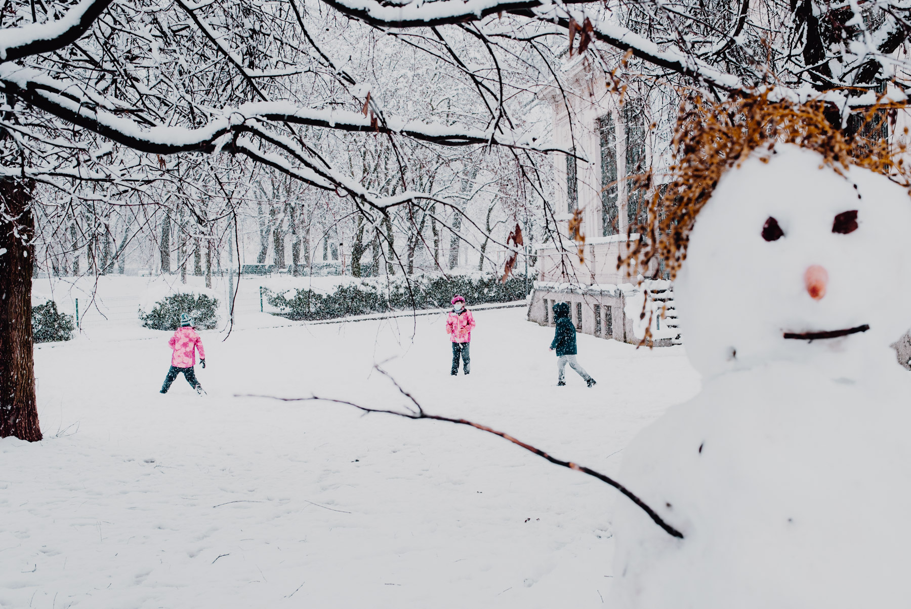 Snow in Milan on December 2020, in Formentano Park there's s snowman and two children playing snowball fights in the background, neve a milano a dicembre 2020 nel parco Formentano al Largo Marinai d'Italia un pupazzo di neve in primo piano svela due bambini che giocano lanciandosi palle di neve sullo sfondo