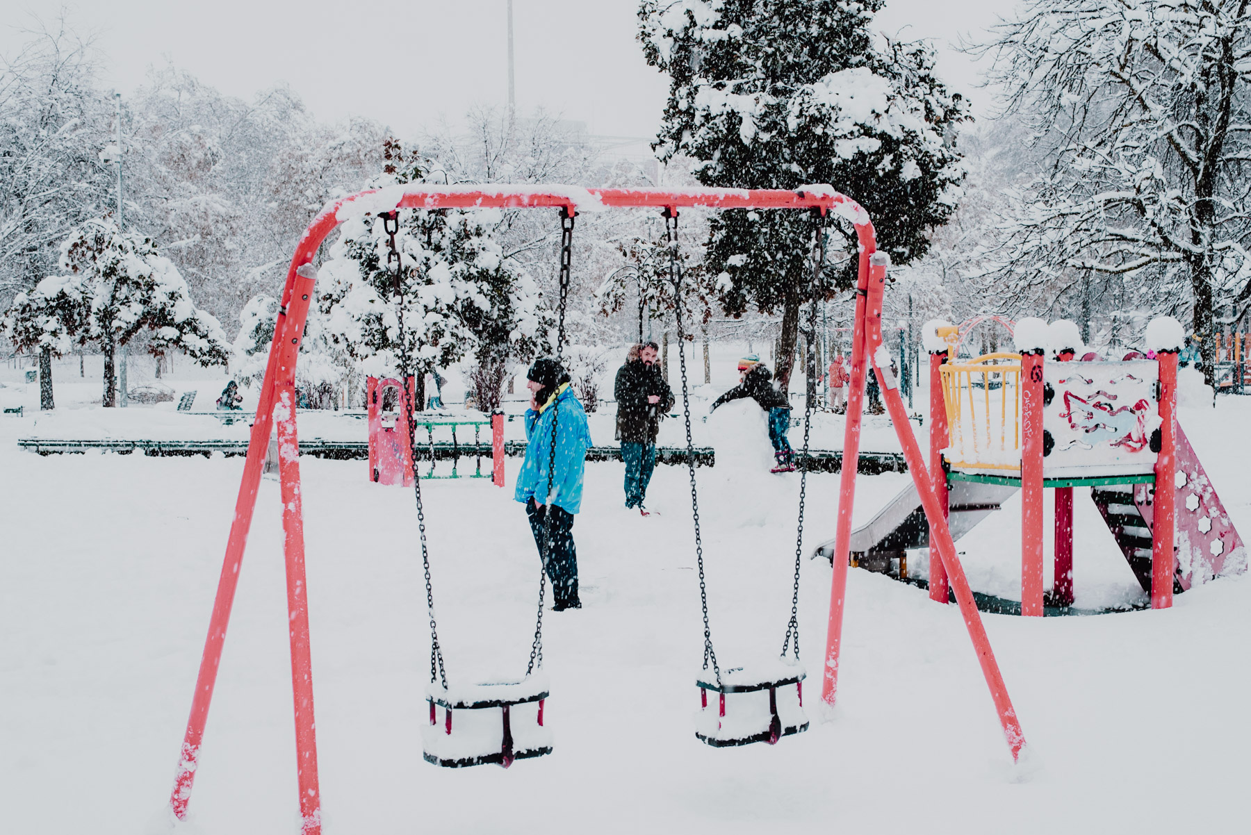 Snow in Milan on December 2020, people standing and talking in the middle of a playground, neve a Milano a dicembre 2020, persone si trovano per giocare e parlare nell'area giochi per bambini
